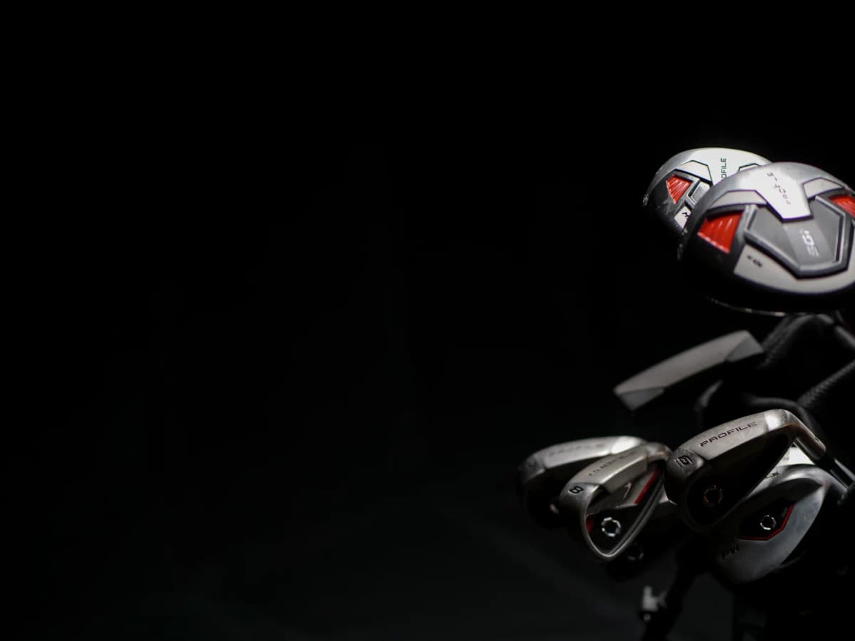 Artistic close-up image of modern golf clubs with dramatic lighting on the club heads.